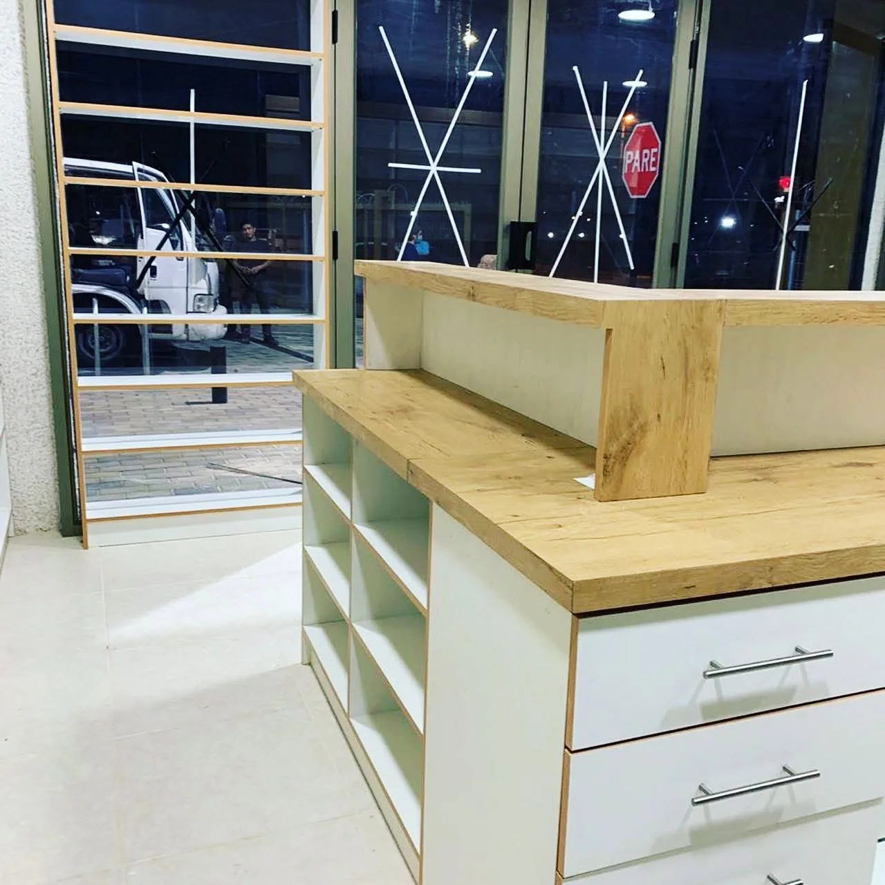 Mostrador farmacéutico en madera con cajones, vitrinas y estantes abiertos