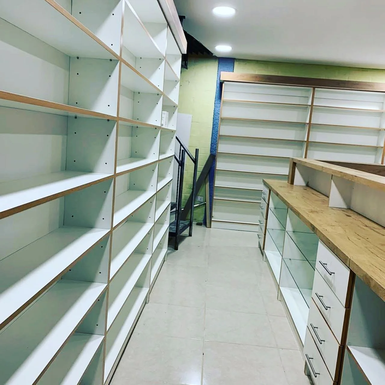 Pasillo de farmacia con estanterías perimetrales y módulo central de atención