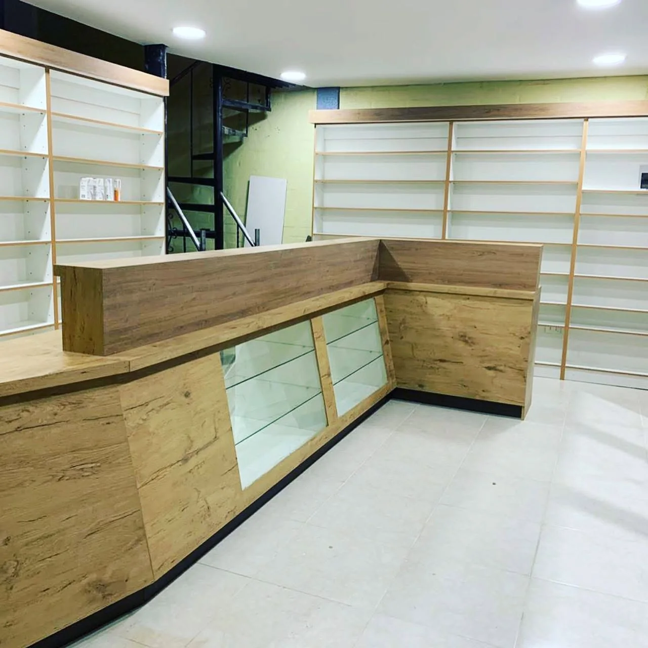Vista general de farmacia con mostrador de madera, vitrinas y estanterías