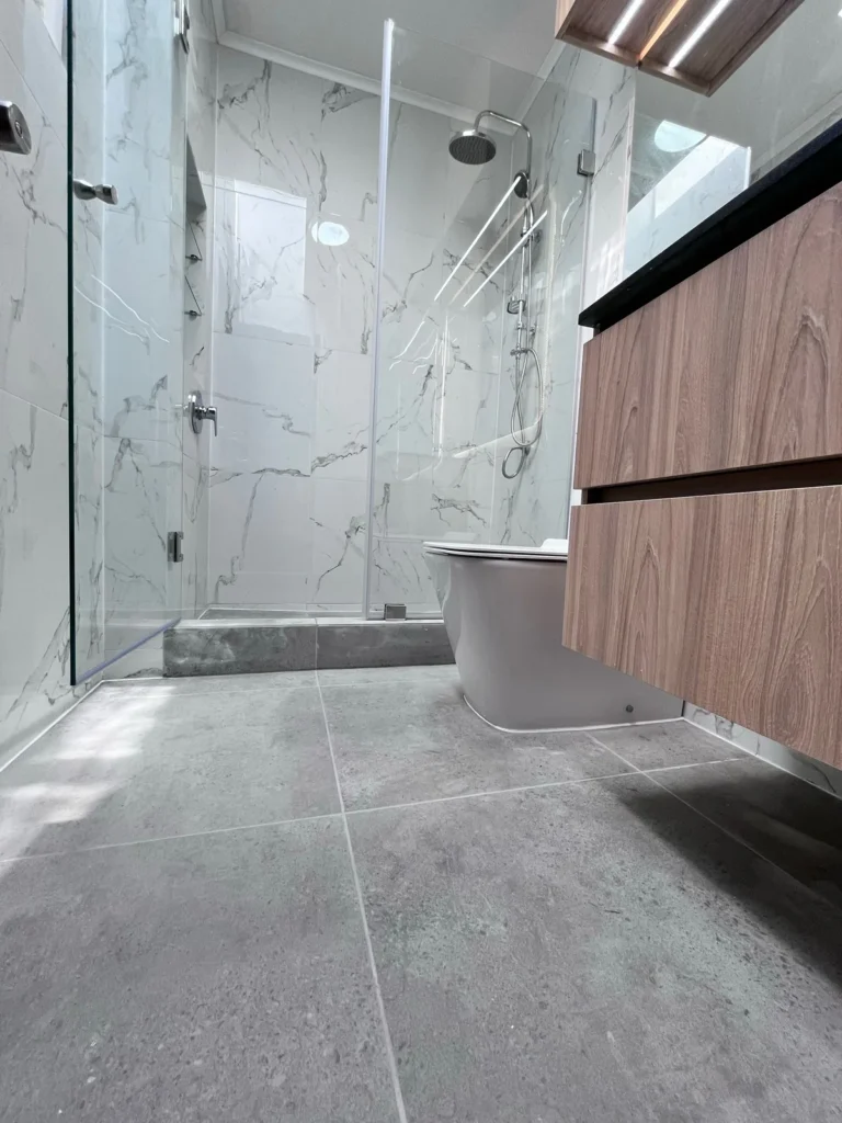 Baño revestido en mármol con vanitorio de madera, vista 1, mobiliario a medida de Muebles GC