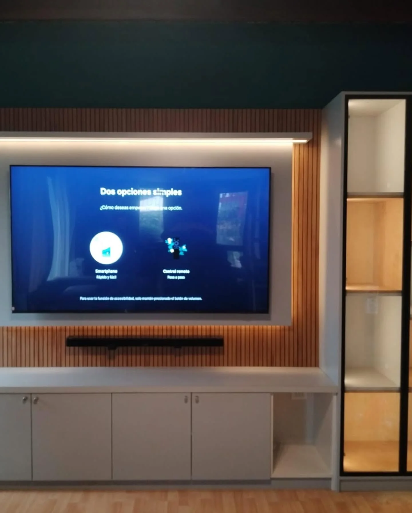 Vista frontal del rack de TV con panel listonado, vitrina iluminada y almacenamiento inferior